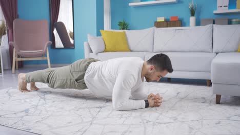 Young-bodybuilder-man-making-planks-at-home-alone.